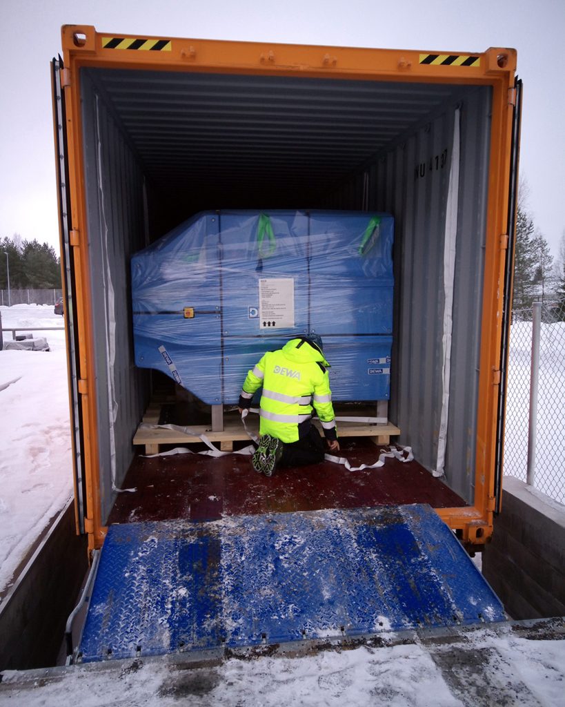 Dewaco employee securing an AURA PRESS 26 belt filter press inside a standard shipping container, highlighting easy and efficient logistics for sludge dewatering equipment deliveries worldwide.