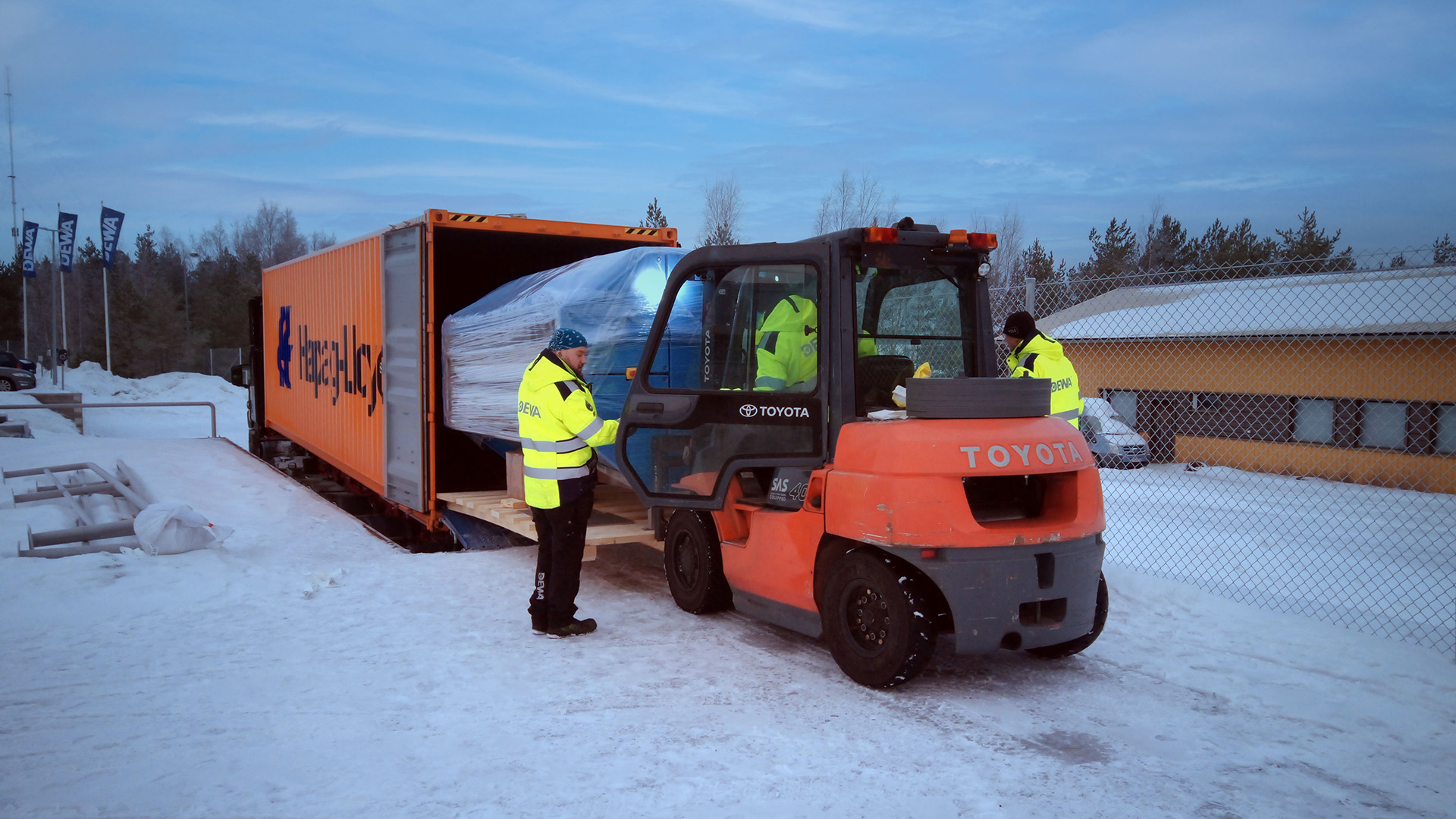 DEWA AURA PRESS 26 being loaded into a standard shipping container at Dewaco's snowy production site in Finland, showcasing container-friendly sludge dewatering equipment for global water treatment logistics.